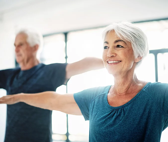 An elderly man and woman doing some simple exercising