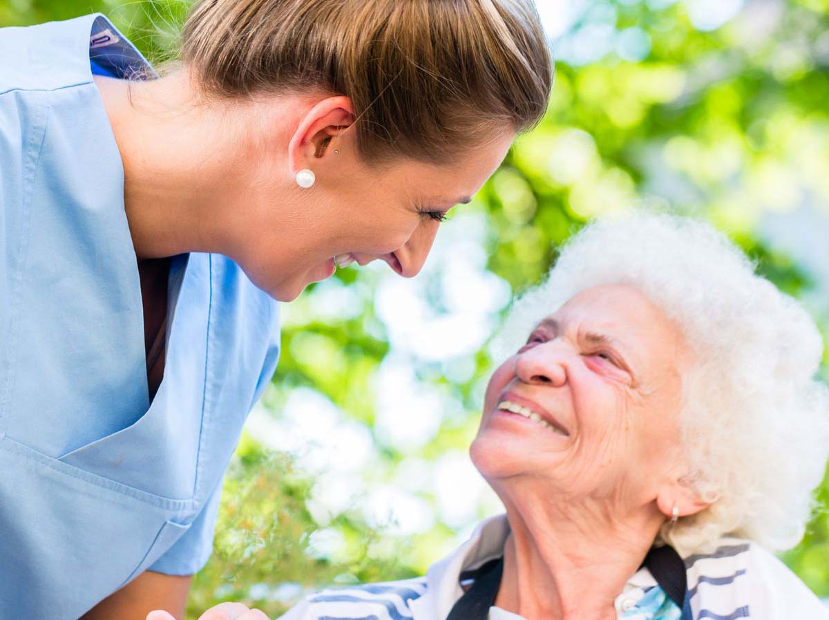 a happy nurse and elderly woman-the nurse is taking care of the elderly woman