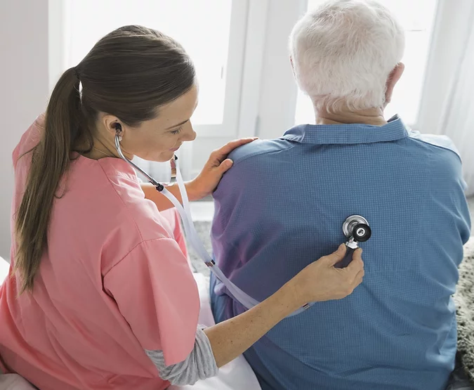 a doctor placed a stethoscope on the back of an elderly man to hear his lungs.