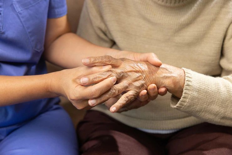 A picture of a caregiver massaging finger of elderly woman in painful swollen gout