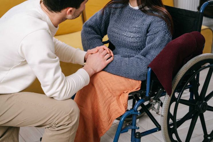 A young doctor giving support and comfort to a lady on a wheel chair