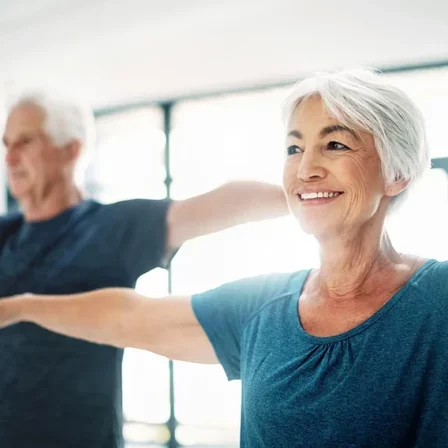 An elderly man and woman doing some simple exercising